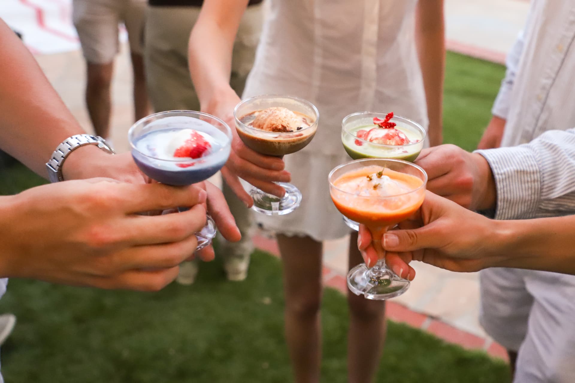 Four guests raising Fogato coupes in a toast on a lawn