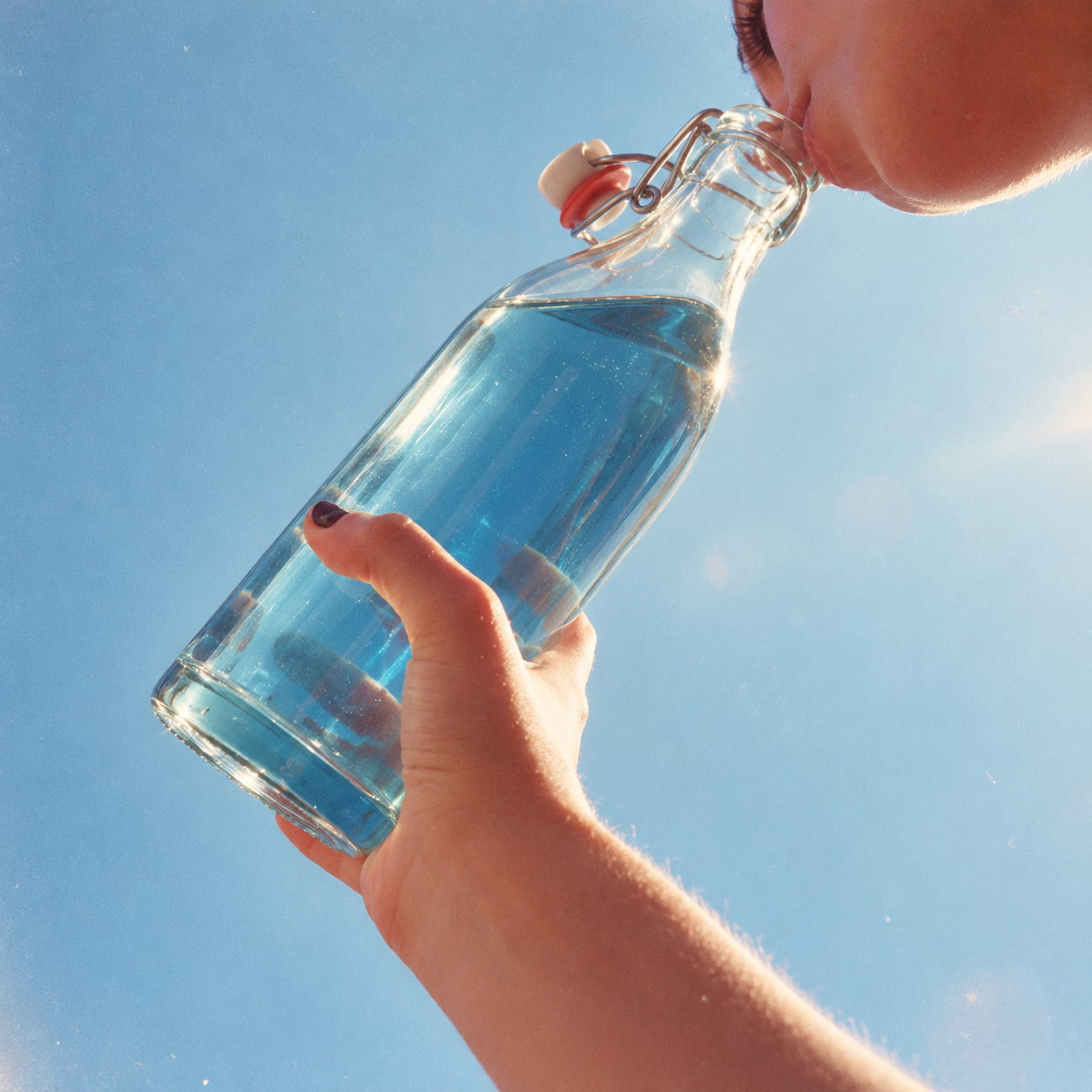 Butterfly blue chamomile tea poured from a swing-top glass bottle against the sky